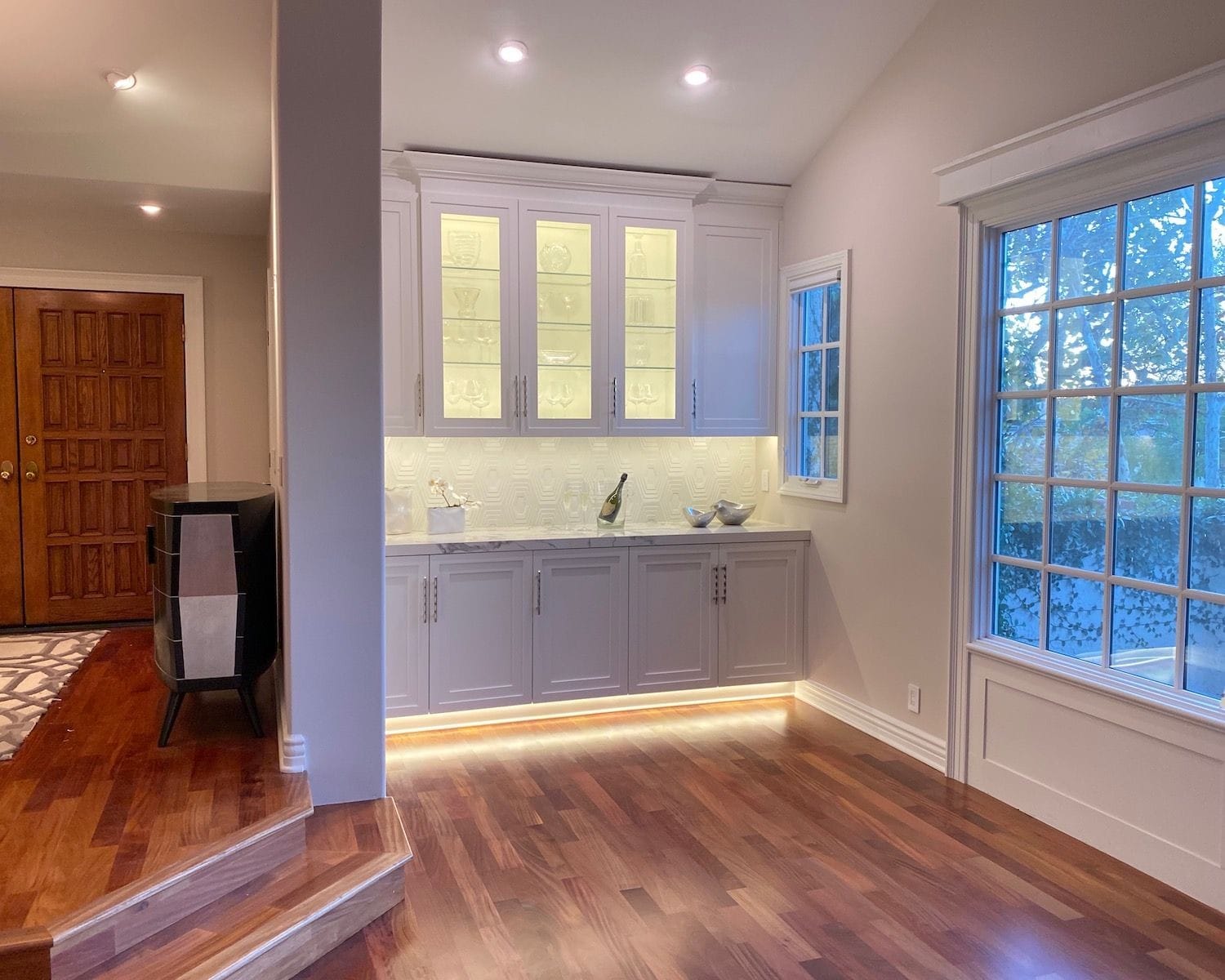 Glass upper cabinets with dimensional Walker Zanger tile backsplash and lighted toe kick.