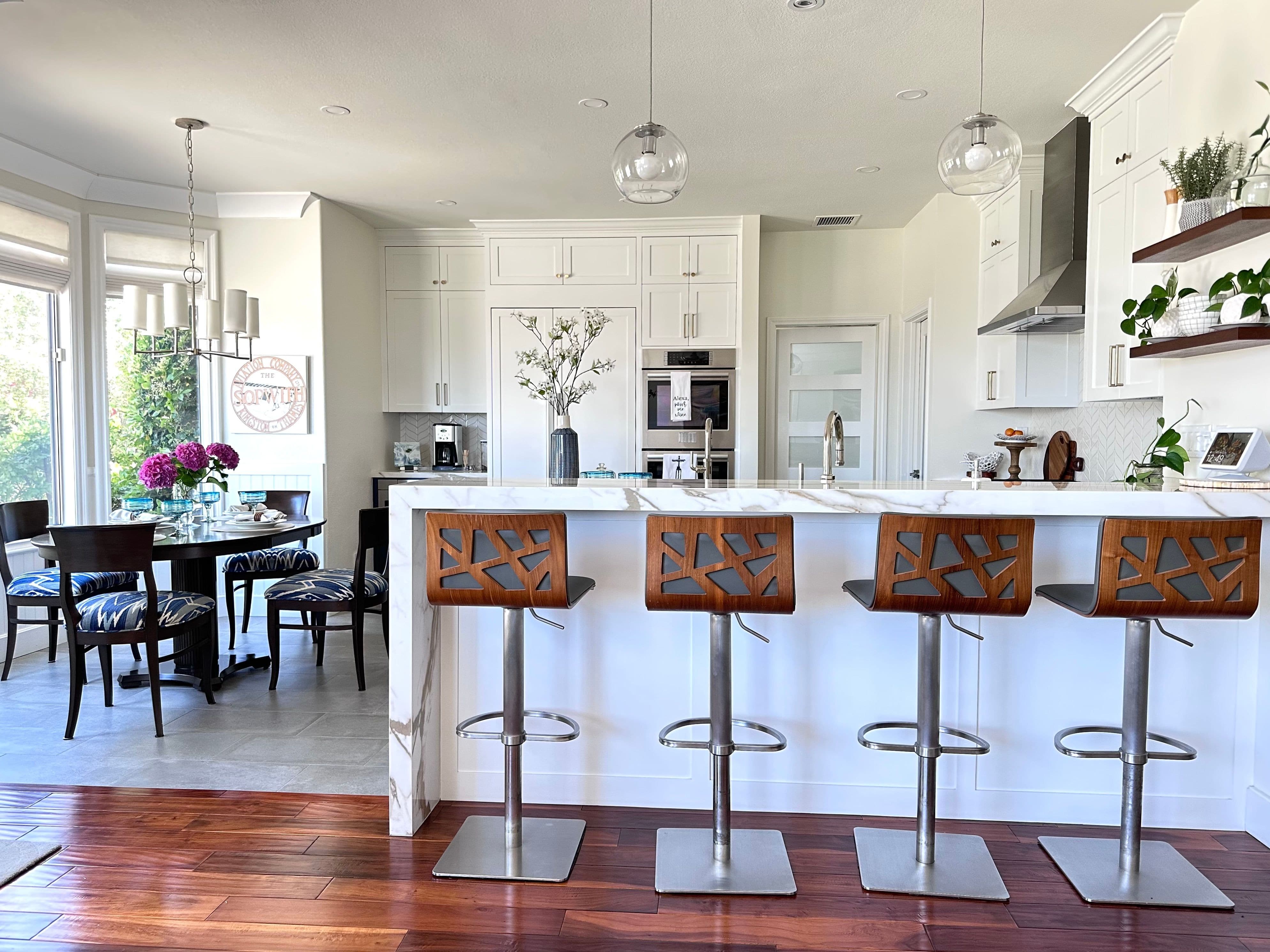 Thibaut upholstered kitchen chairs, White cabinets with shaker style and marble counters. Pendant lights.